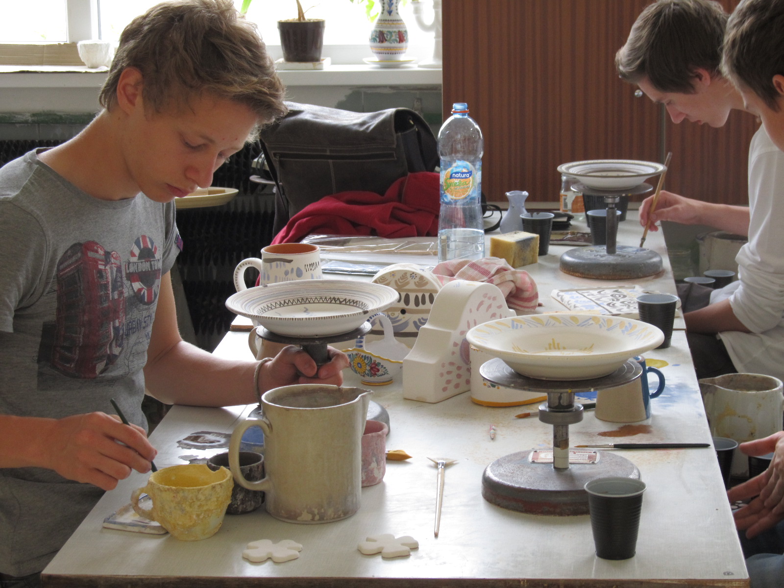 Študent pri maľovaní keramiky